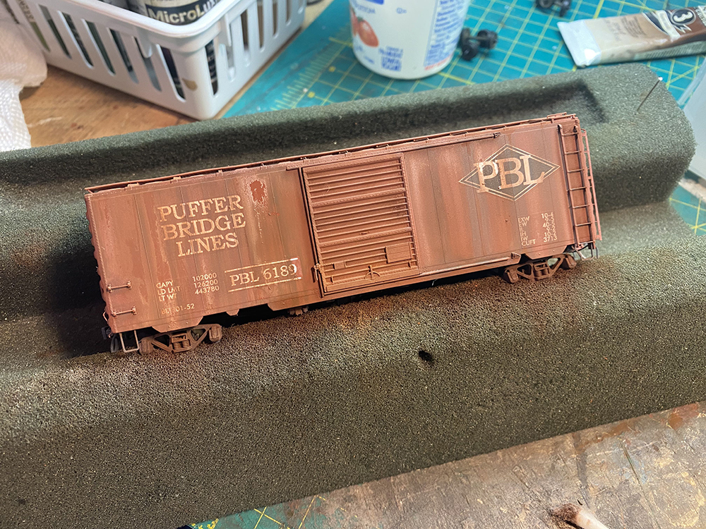 Brown model boxcar on workbench with faded paint and rust