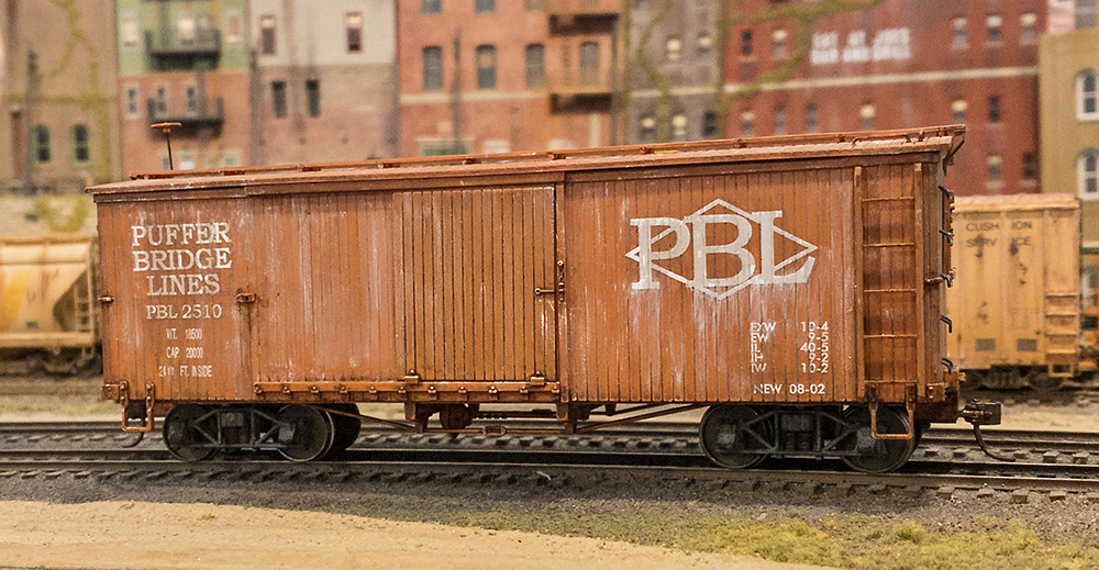 Car Swap Project part 9: Lessons learned: Reddish brown oversized plastic model boxcar on smaller, finished model railroad track