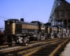Black-and-gold Monon Railroad diesel locomotives under concrete coaling tower