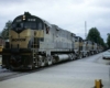 Black-and-gold Monon Railroad diesel locomotives with freight train on street trackage
