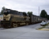Black-and-gold Monon Railroad diesel locomotive with passenger train on street trackage