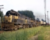 Four black-and-gold Monon Railroad diesel locomotives with freight train on curve