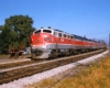 Gray-and-red Monon Railroad diesel locomotives with passenger train on curve