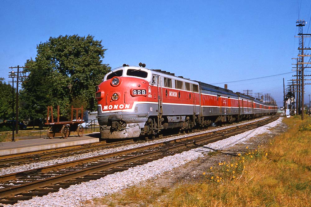 Gray-and-red Monon Railroad diesel locomotives with passenger train on curve