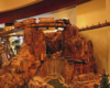 A steam train crosses a bridge over a model of the Hoover Dam