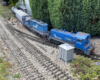 two blue model locomotives rounding a curve on a garden railroad