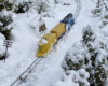 model locomotive with yellow snowplow pushing through snow on garden railroad
