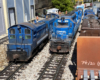 two blue model locomotives on track of garden railroad