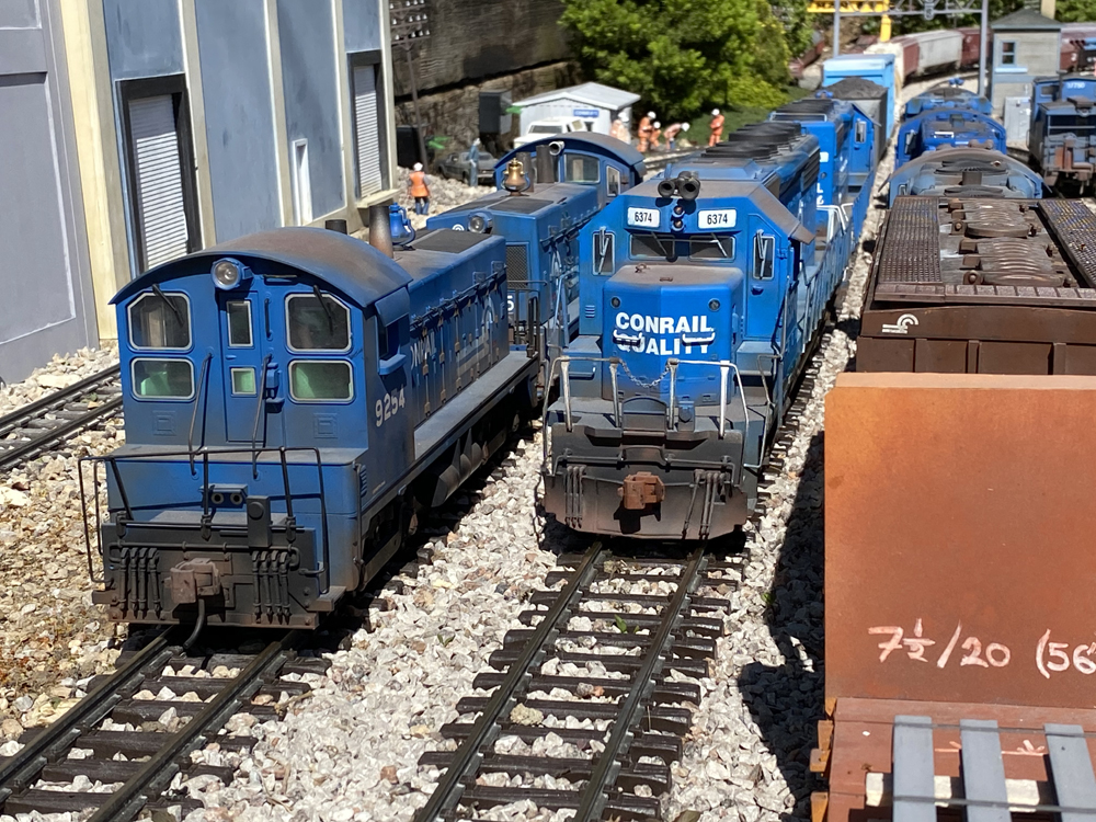 two blue model locomotives on track of garden railroad