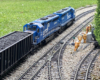 two blue model engines nearing a curve with model people to the right