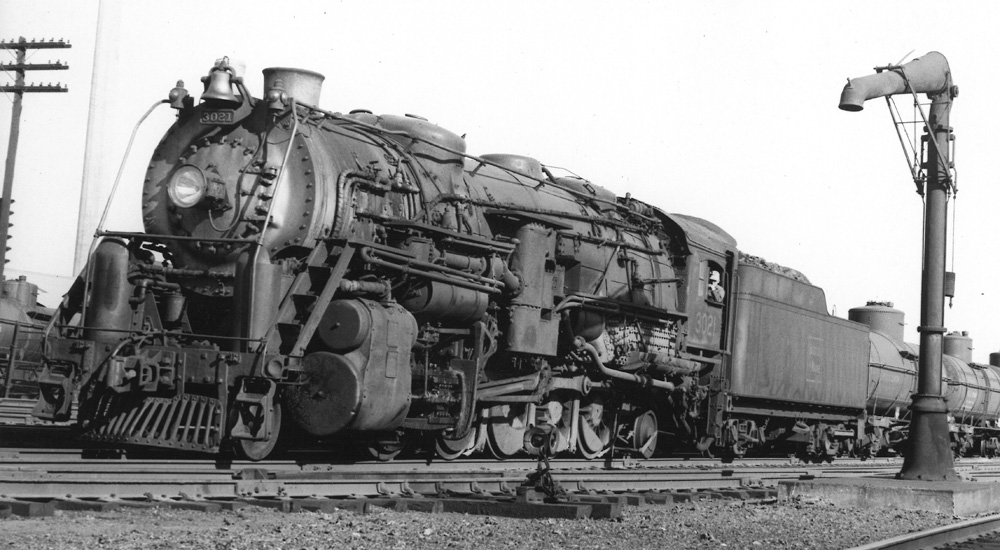 A black-and-white photo of a Boston & Maine 2-10-2 steam locomotive with a booster engine on its rear tender truck