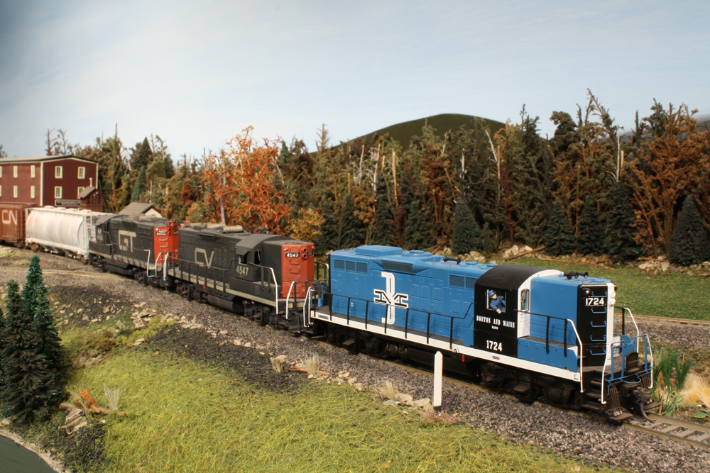 A blue model diesel engine and train in rural New England