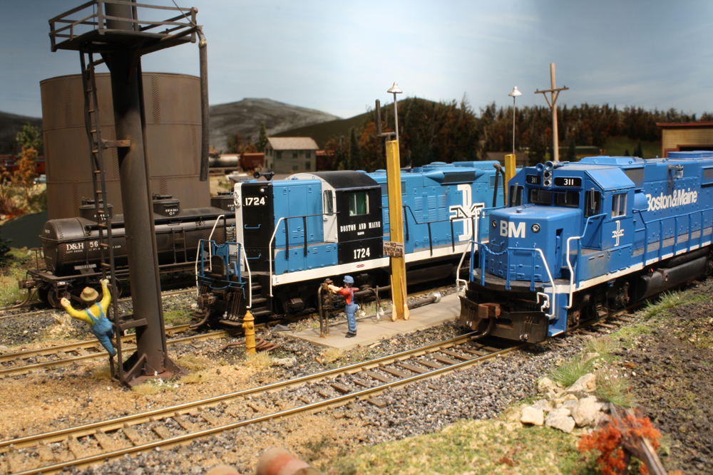 Two blue diesel engine models idle at a fueling facility