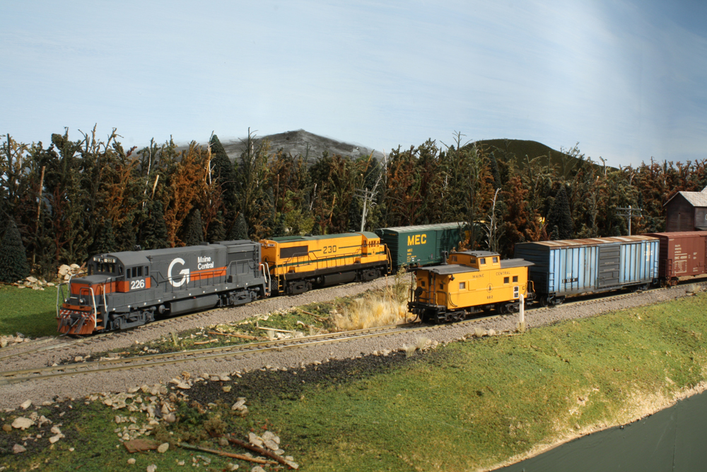 Two model train engines meet the caboose of another train