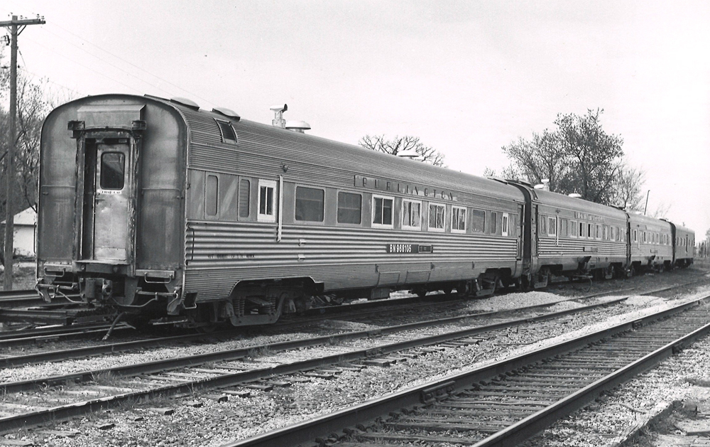 Black-and-white photo of four passenger cars on a siding.