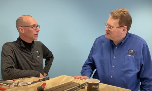 Two men speaking over a model train table.
