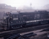 Black-and-white diesel locomotive leading train in fog