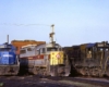Three diesel locomotives lined up in front of brick enginehouse
