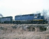 Blue-and-yellow and black diesel locomotive with freight train on low bridge