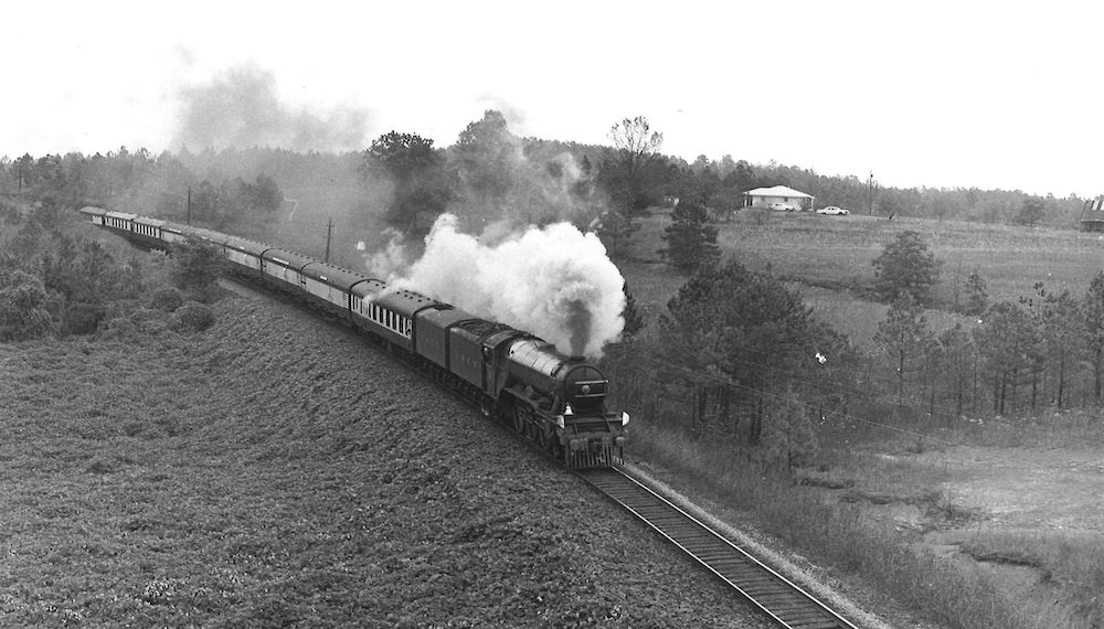 British steam train passing through field.