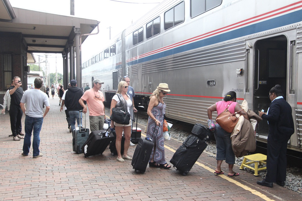 People lined up to board bilevel passenger cars