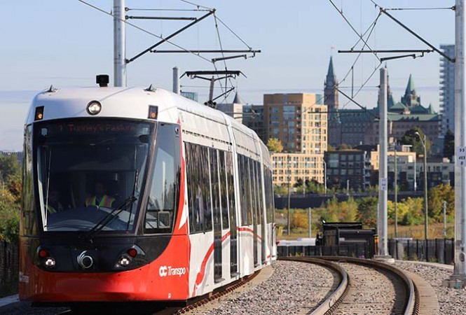 Red and white light rail train rounds curve