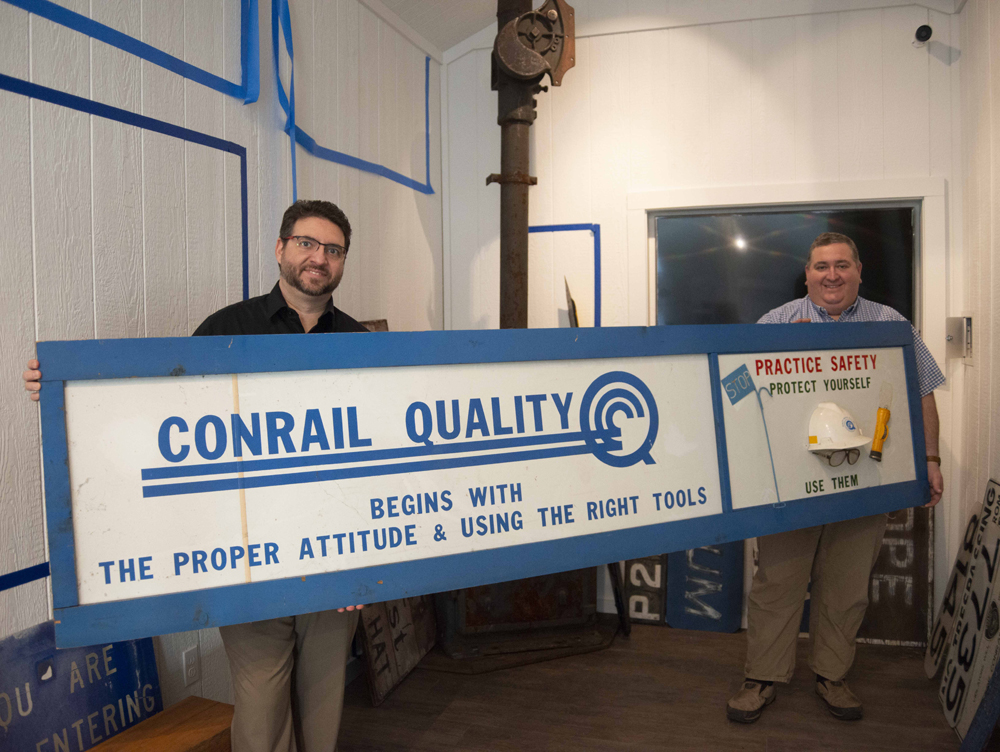 Two men holding "Conrail Quality" sign