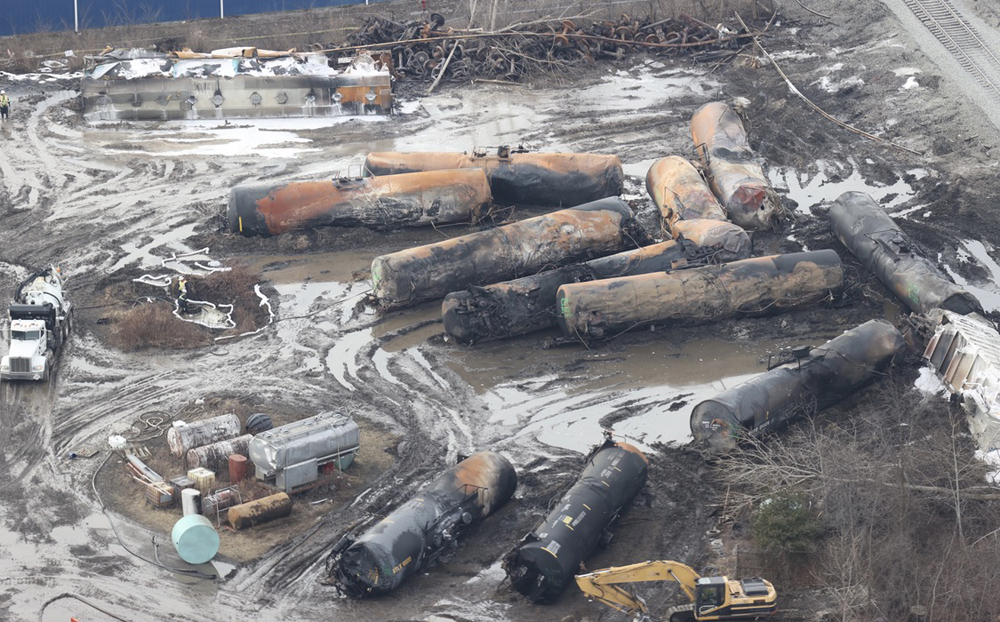 Workers and equipment around burned out tank cars