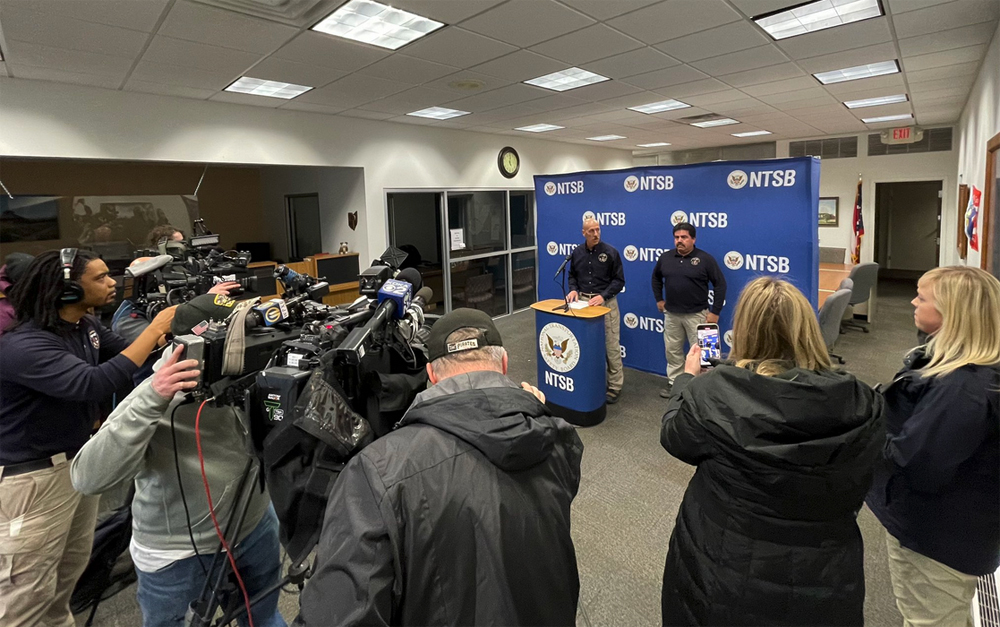 Man speaks at podium facing TV cameras