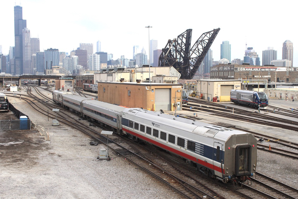 Passenger train approaches Chicago with skyline in distance