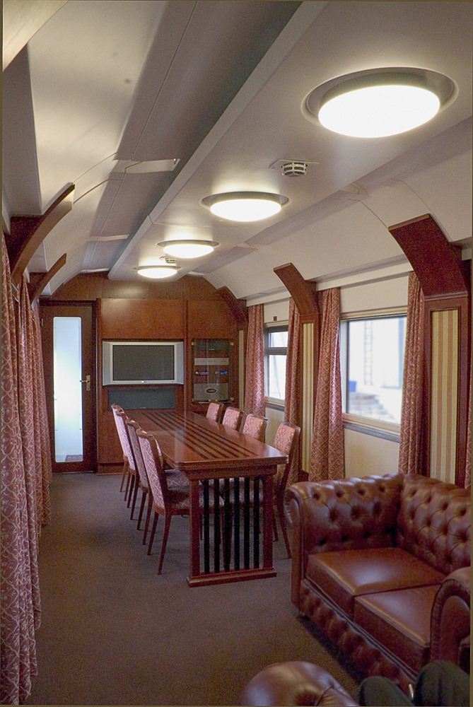 Well-appointed interior of rairoad car with large table and big screen TV.