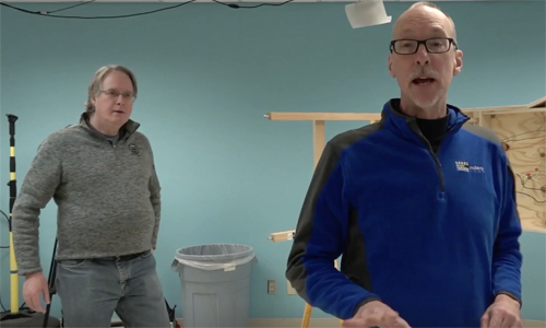 Two men in a model railroad workshop facing the camera.