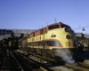 Red, yellow, and black streamlined diesel locomotive with passenger train