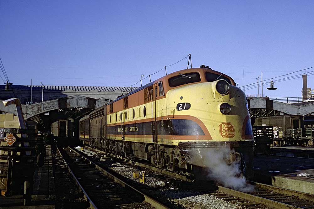 Red, yellow, and black streamlined diesel locomotive with passenger train