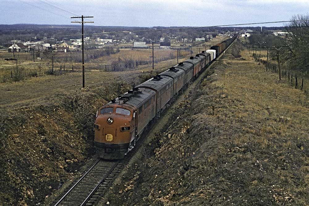Overhead view of seven diesel-powered Kansas City Southern locomotives with freight train