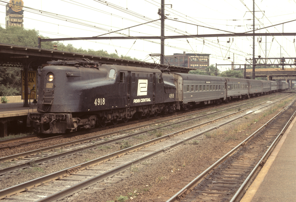 Black painted electric locomotive leading a passenger train in a yard.