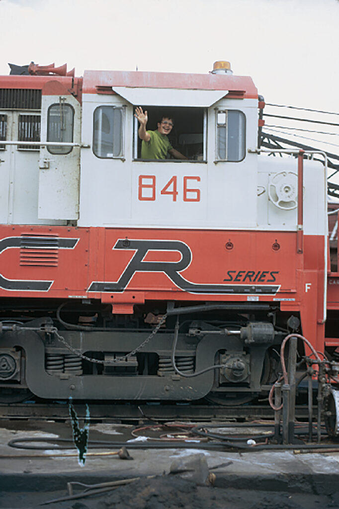 Man waiving from cab of diesel locomotive.