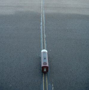 model locomotive on rails across blacktop driveway