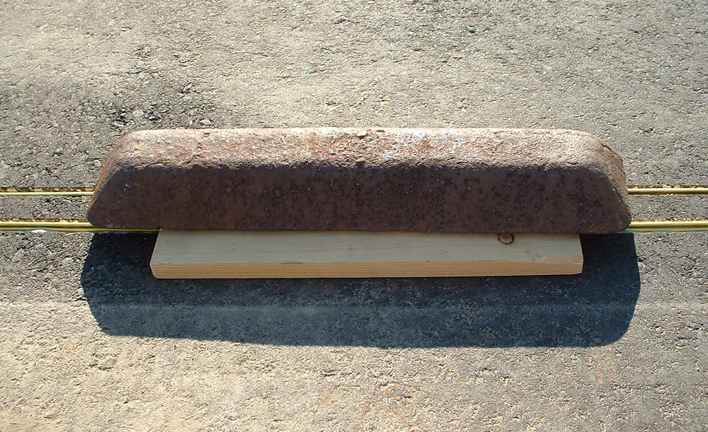 piece of 2x4 with weight on top of track rail