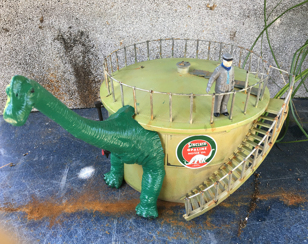 model gas station with green plastic dinosaur on the front