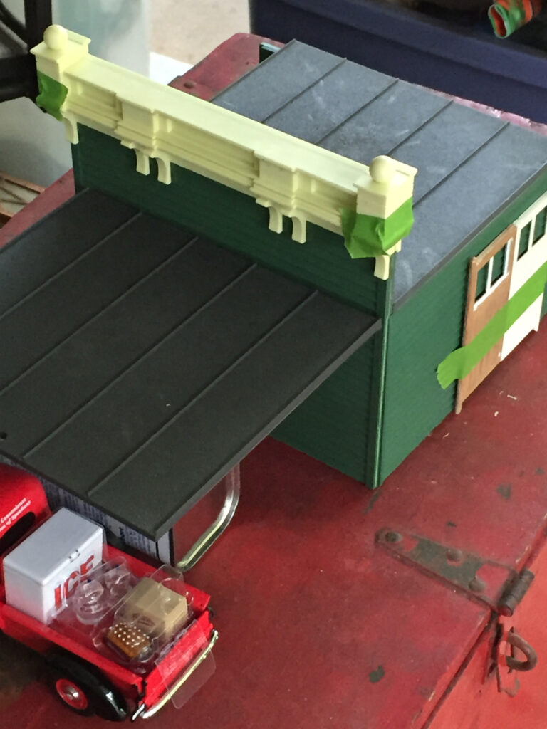 partially completed gas station structure with red pickup truck model near bottom