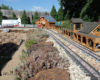 model train rests near structure on garden railroad