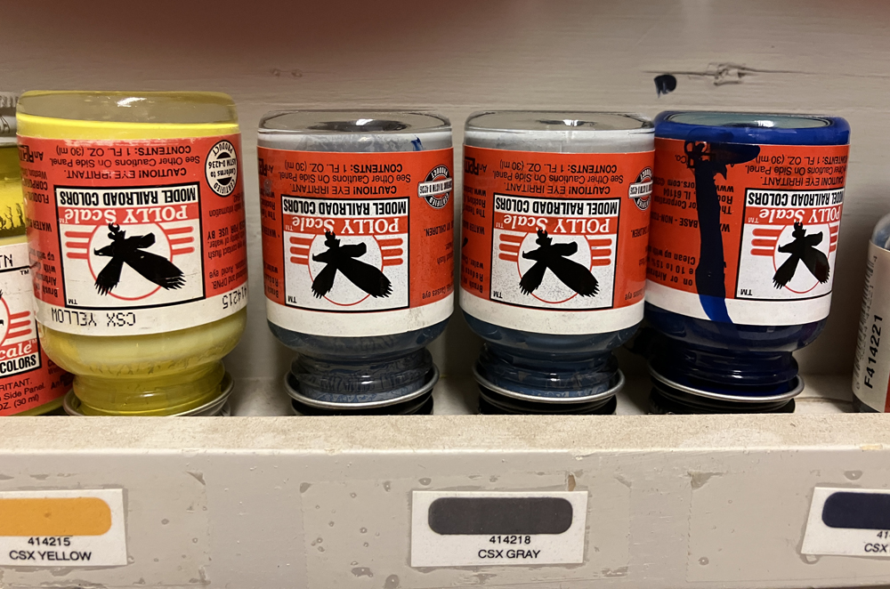 four bottles of paint upside down on shelf