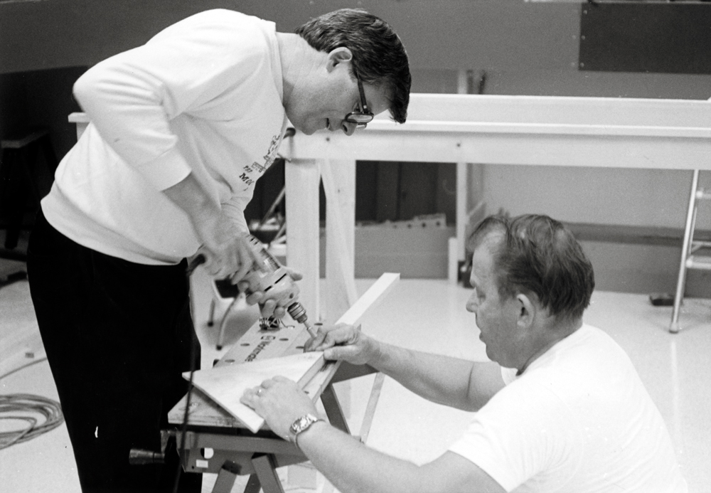 Black-and-white photo of two men building benchwork.
