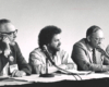 Black-and-white photo of three men at panel discussion.