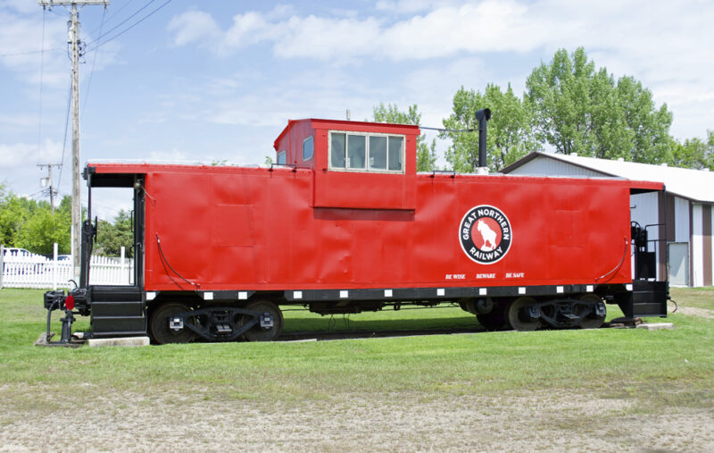 Color photo of red and black caboose at museum.