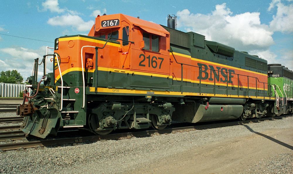 Color photo of locomotive in orange and green paint with yellow stripes.