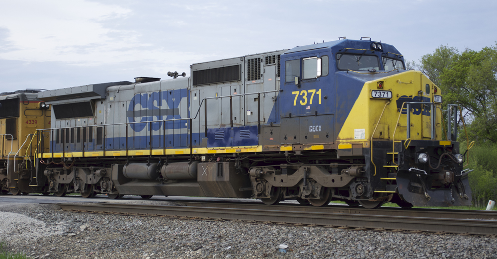 Color photo of gray, blue, and yellow diesel locomotive.