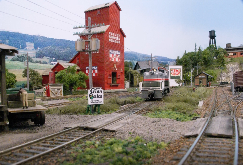 An image of a model railroad layout with a large red grain elevator