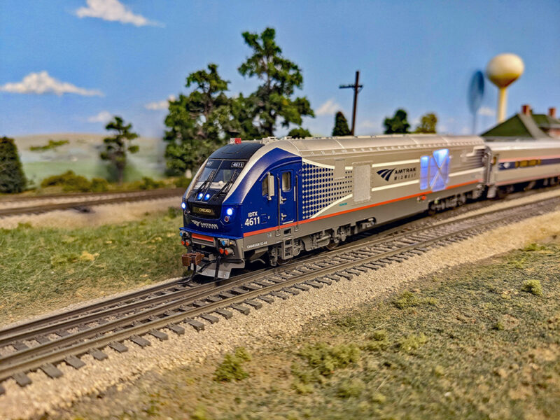 Model of new Amtrak diesel locomotive with passenger car at station